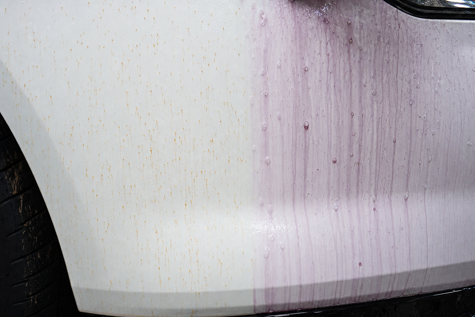 White car panel with orange iron fallout rust spots and purple iron remover chemical reaction