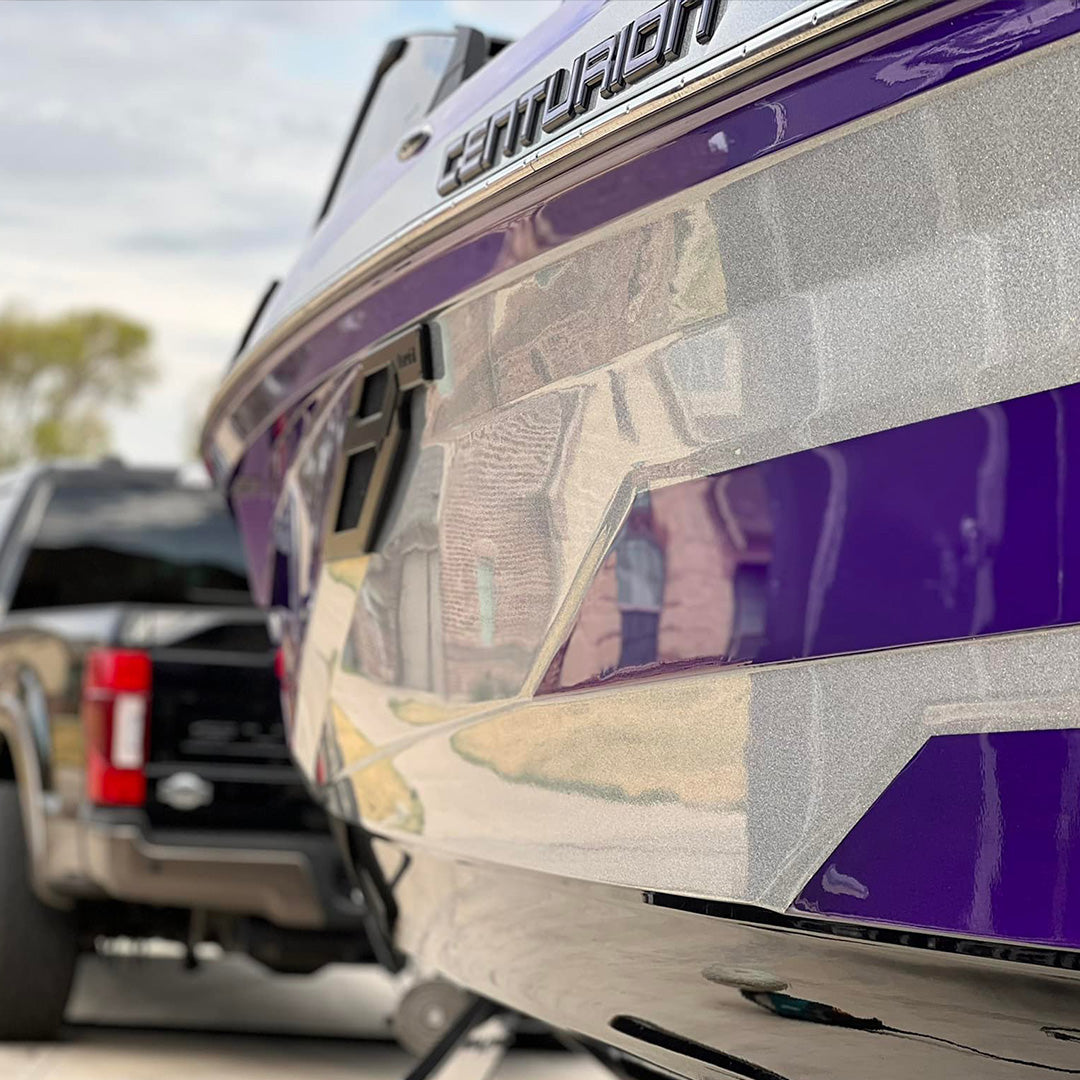 Reflective purple and silver boat hull beside a pickup truck
