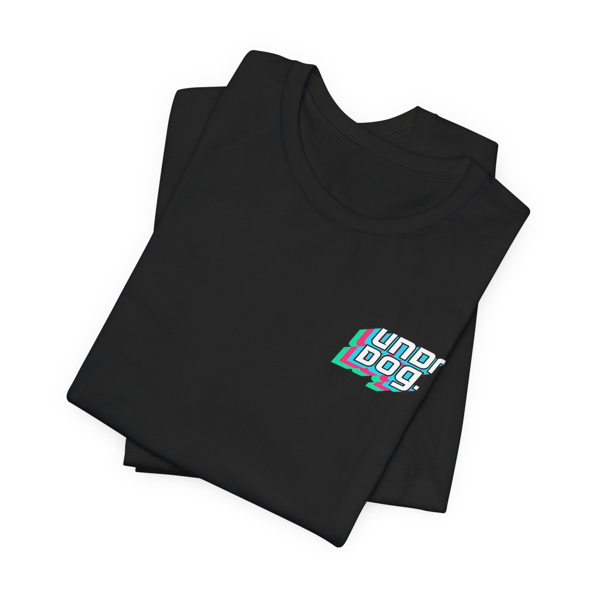 A neatly folded black Printify Unisex Jersey Short Sleeve Tee, crafted from premium Airlume cotton, featuring "underdog" in white multi-colored shadowed text on the left chest. The shirt is shown laid flat on a white background.