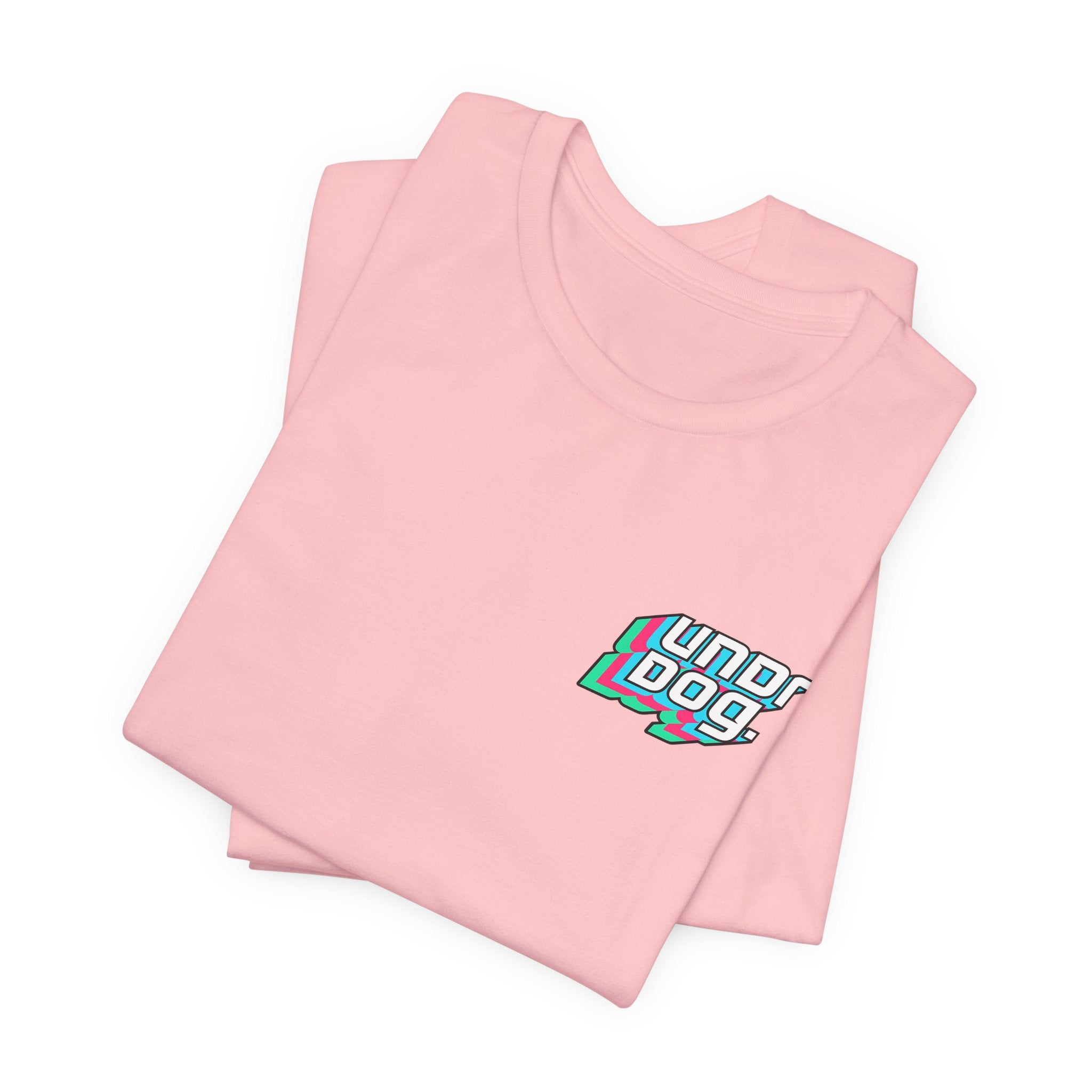 A folded light pink See Yourself In It Retro Sportscar Tee by Printify featuring a colorful “Underdogs” chest graphic in bold, layered white, teal, and pink synthwave style.