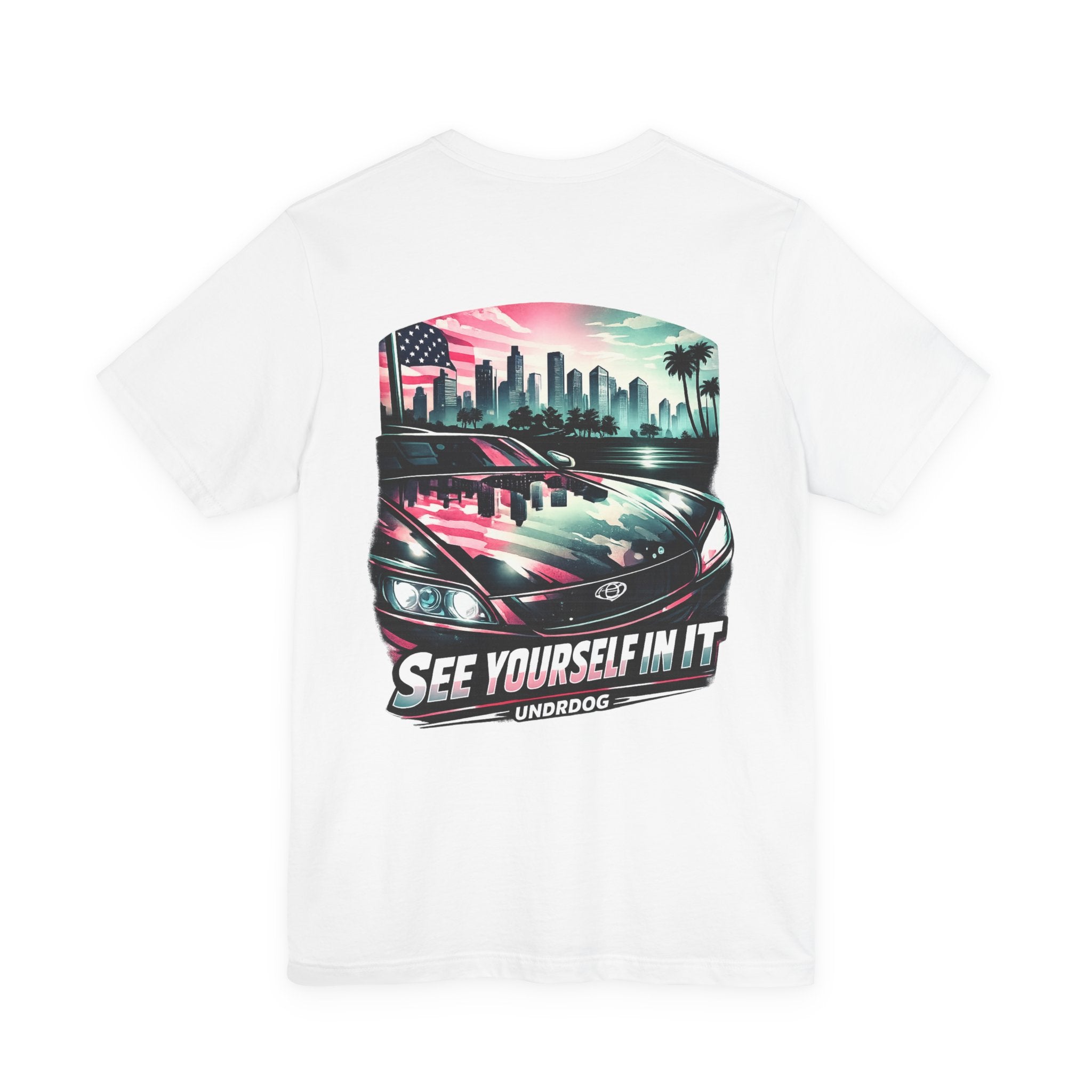 The See Yourself In It Retro Sportscar Tee by Printify features a back graphic of a car hood reflecting a city skyline, palm trees, and an American flag, with "SEE YOURSELF IN IT" and "UNDRDOG" boldly displayed below.