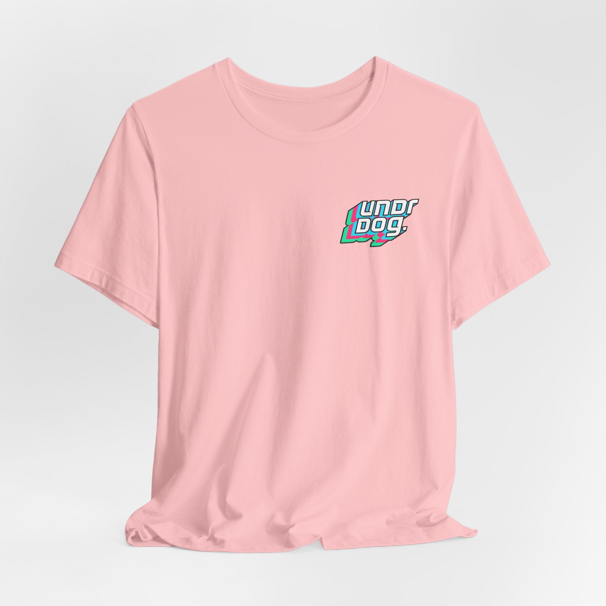 The See Yourself In It Retro Sportscar Tee by Printify is a light pink synthwave shirt featuring a small, colorful "Undr Dog" logo on the left chest, shown on a plain white background.