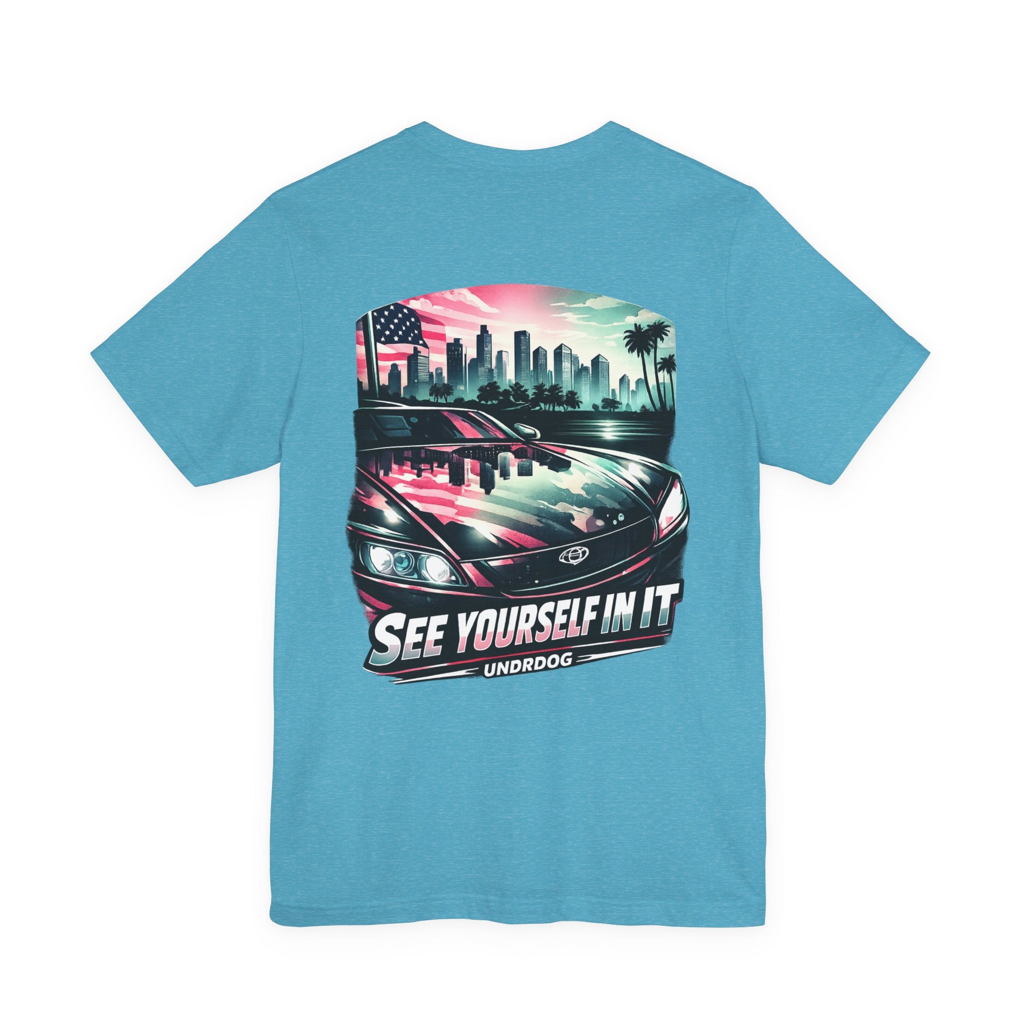 The See Yourself In It Retro Sportscar Tee by Printify features a blue vintage car with a city skyline, palm trees, an American flag, and the phrases "SEE YOURSELF IN IT" and "UNDRDOG" below the graphic.