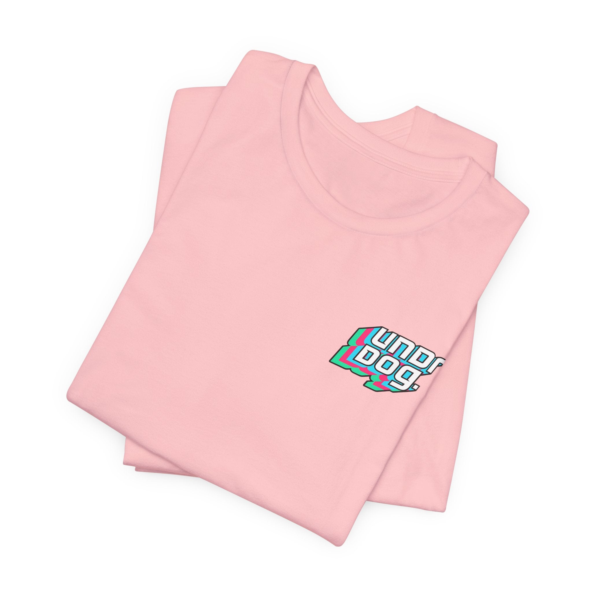 A folded light pink Printify Unisex Jersey Short Sleeve Tee featuring a small, colorful "underdog" graphic with blue, green, and white outlines printed on the left chest area. Crafted from soft Airlume combed cotton.