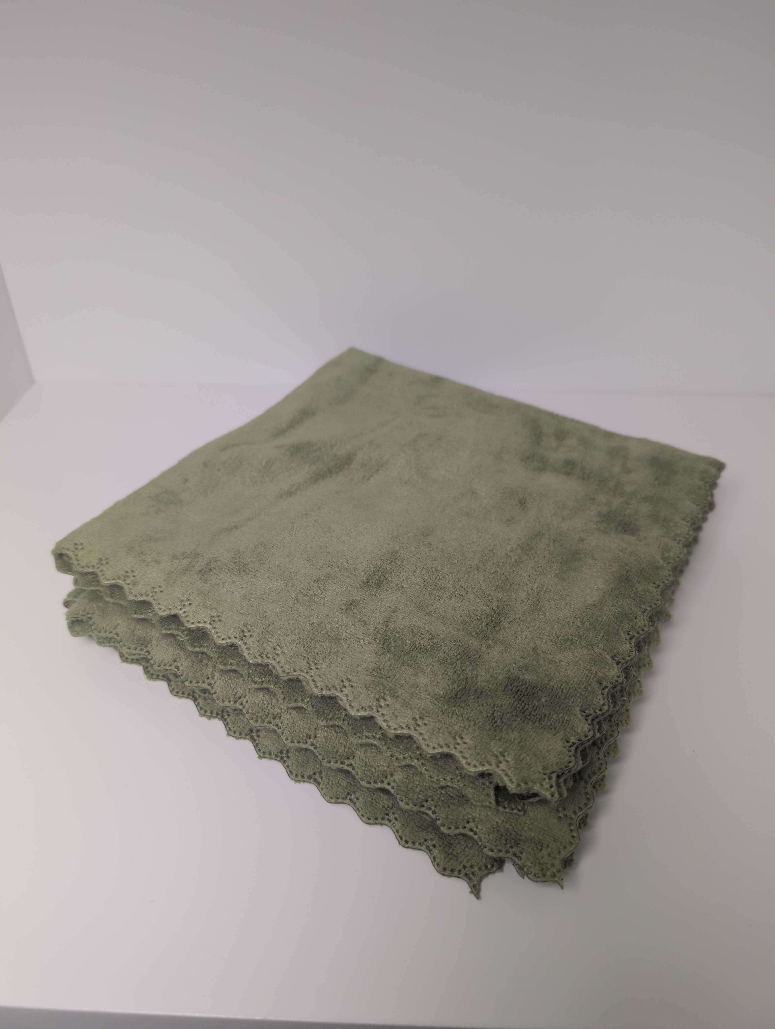 The Green Weft Towel by Undrdog Surface Products, a folded green microfiber towel with scalloped edges, is displayed on a plain white surface.