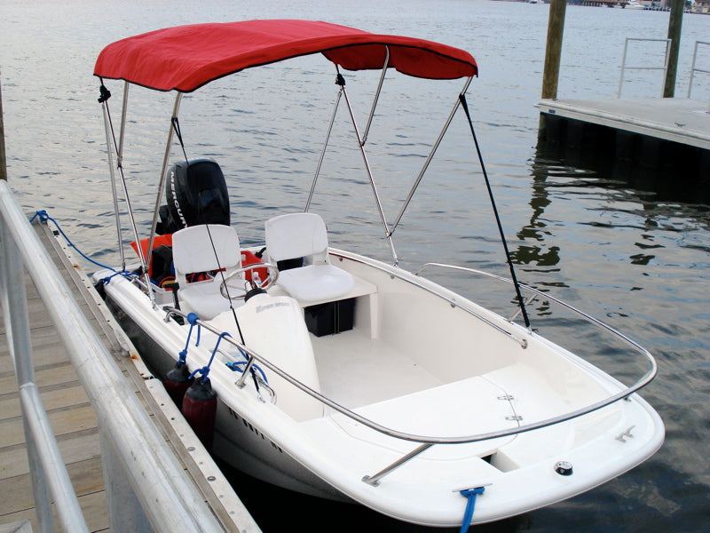 White boat at a dock with a red fabric Bimini top supported by metal tubing