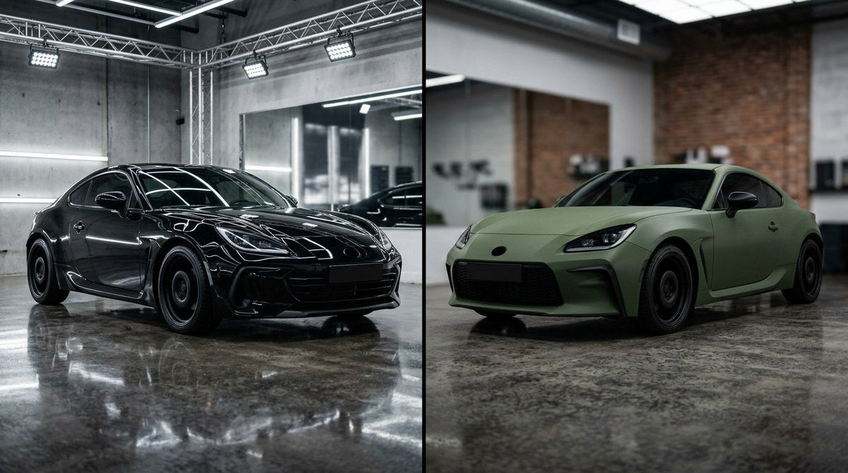 Side by side comparison of a glossy black ceramic coated sports coupe next to the same coupe in a matte green vinyl wrap in a professional detailing studio