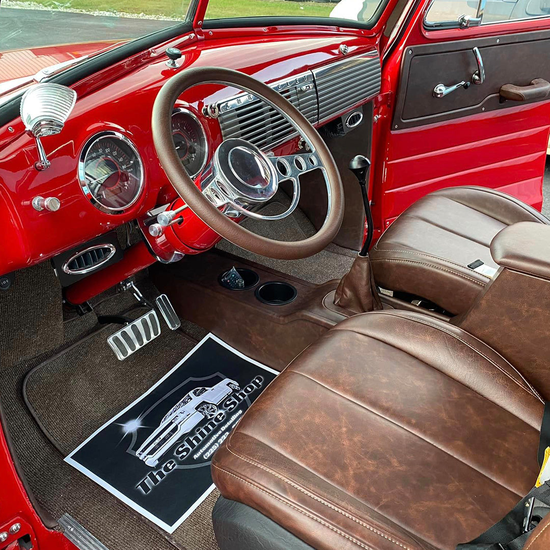 Red classic vehicle interior with brown upholstered seats and steering wheel