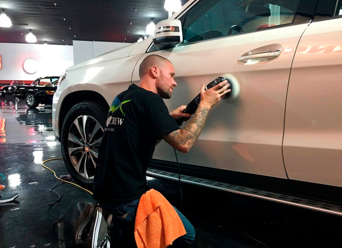 Professional detailer machine polishing an SUV before ceramic coating