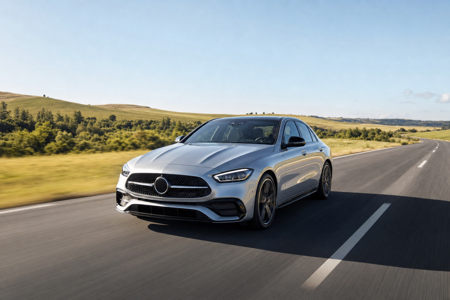 Glossy silver car driving on an open summer highway with sun reflecting off the hood