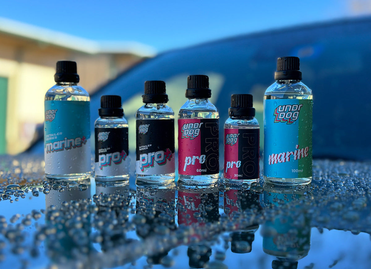 Undrdog Pro and Marine ceramic coating bottles on a water-beaded hood