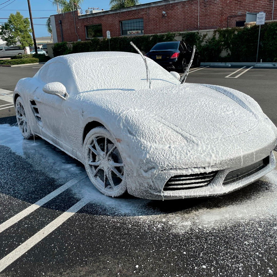 Sports car covered in wash foam with its windshield wipers raised