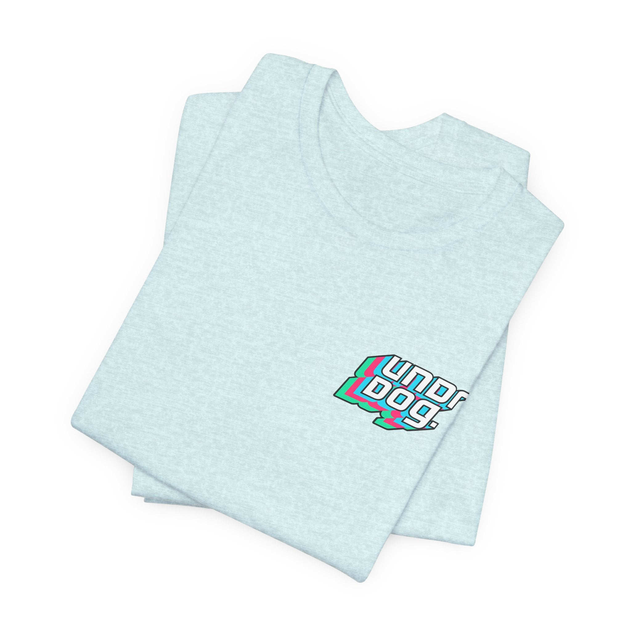 A folded Printify See Yourself In It Retro Sportscar Tee in light blue displays a small "Underdogs!" graphic in white, teal, pink, and black on the left chest. Another identical vintage-style shirt is stacked underneath.