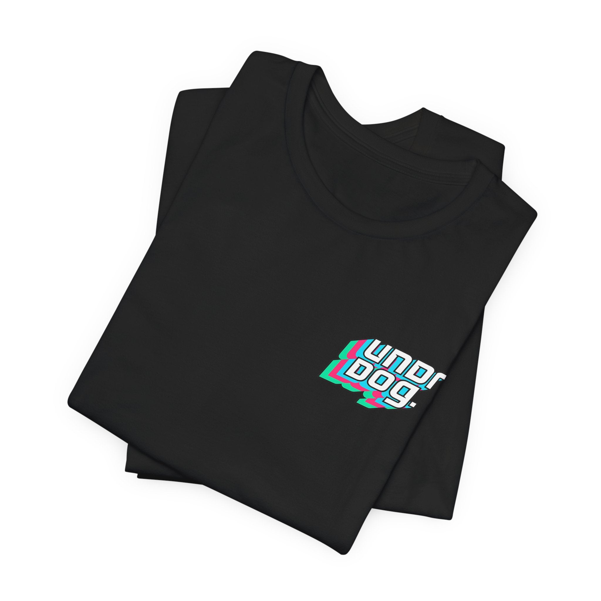 A folded black "See Yourself In It Retro Sportscar Tee" by Printify featuring bold, colorful "UNDERDOG" text with a stylized teal, pink, and white shadow effect on the chest.